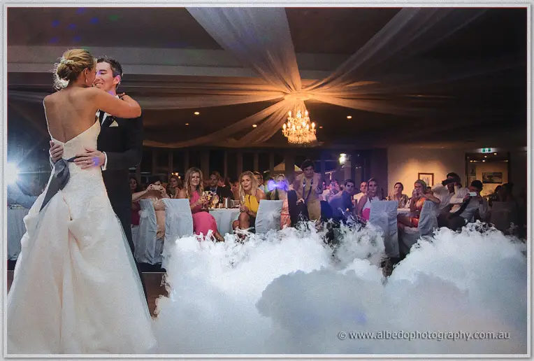 First dance for Lauren and Ryan over billowing white fog as guests watch from packed tables beneath a chandelier