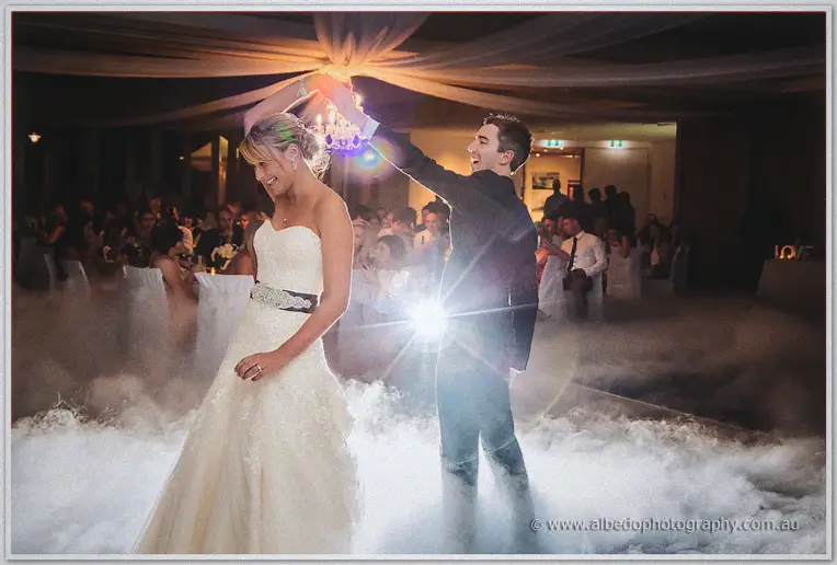 Ryan twirling Lauren under his arm through drifting fog on the dance floor, guests watching from the glow