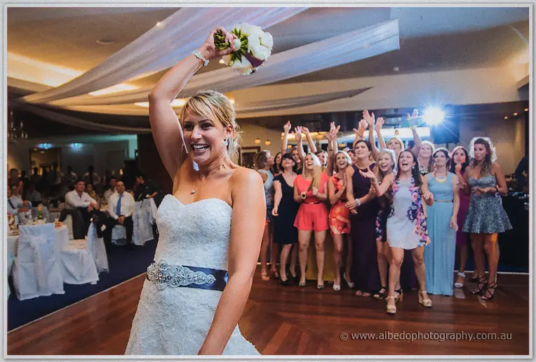 Lauren waving her bouquet aloft as a crowd of keen single girls reaches skyward behind her