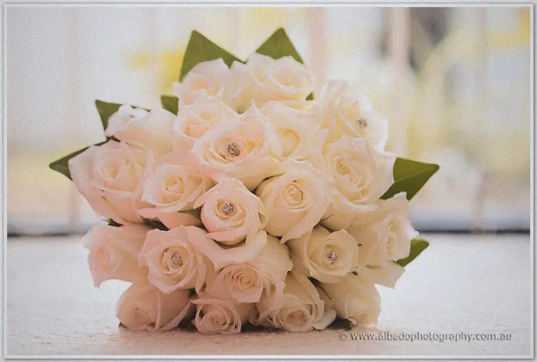 A posy of blush roses studded with crystal pins rests on a sill in glowing backlight