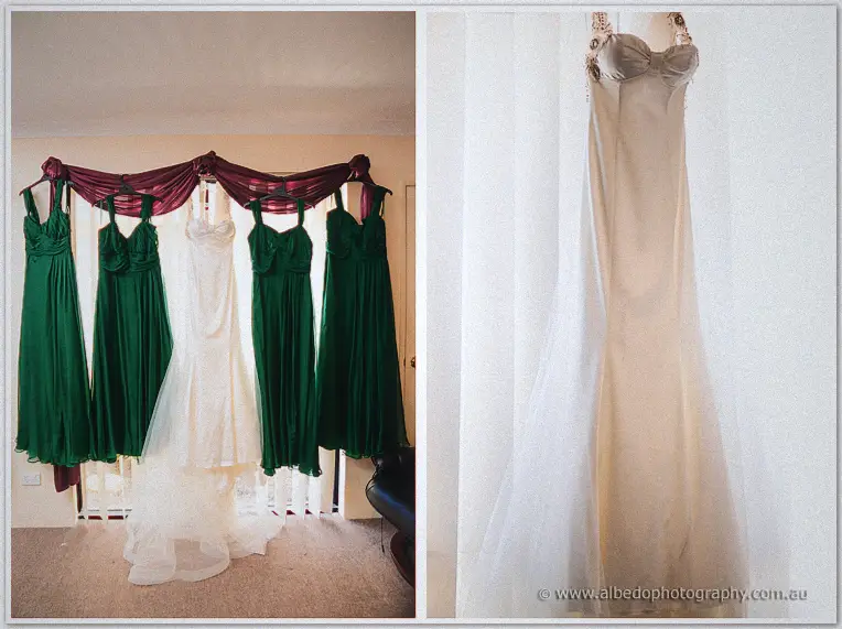 Four emerald bridesmaid dresses hang around Cristal's white gown beneath a burgundy drape