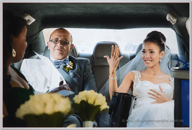 Cristal waves from the limousine seat beside her father in a white jacket and blue bow tie
