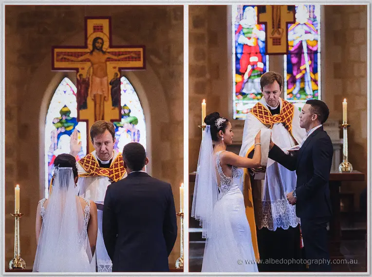 Priest blesses the couple beneath the golden crucifix, then watches their shared candle in stained light.