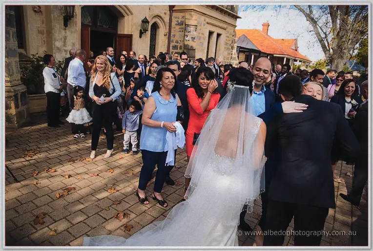 Cristal greets a crowd of family and friends spilling across the paved courtyard outside the church.
