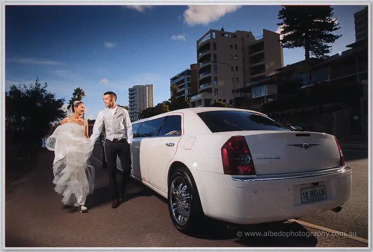 Cristal lifts her gown laughing as she and Troy stroll along the river road beside the white limousine.