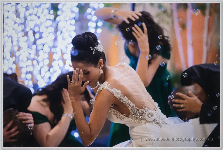 Cristal ducks laughing as bubbles settle on the beaded lace back of her gown.