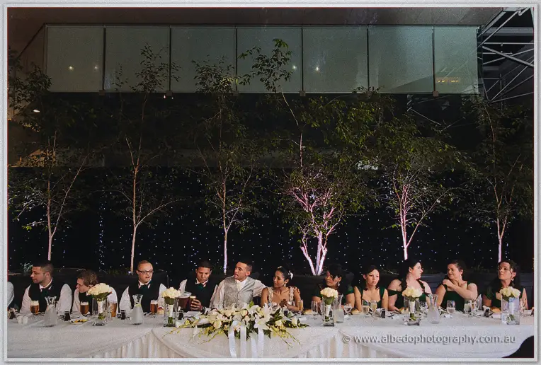 The bridal table sits beneath floodlit trees and a curtain of stars at the courtyard reception.