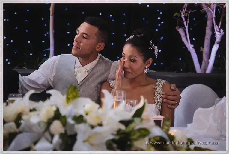 Cristal dabs a tear as Troy's arm settles around her shoulder during the speeches.