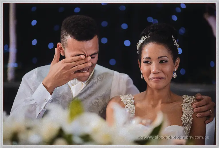 Troy wipes his eyes while Cristal fights tears beside him at the bridal table.