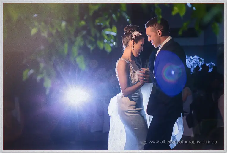Cristal and Troy dance forehead to forehead as a backlit glow and lens flare wash the night courtyard