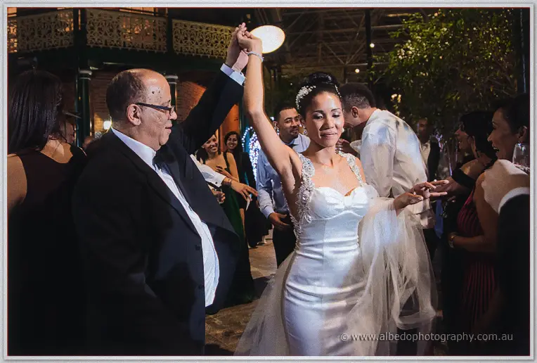 Cristal spins on the dance floor with an older gentleman while smiling guests look on around the courtyard