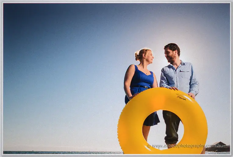 Grinning at each other through a giant yellow swim ring on the empty beach