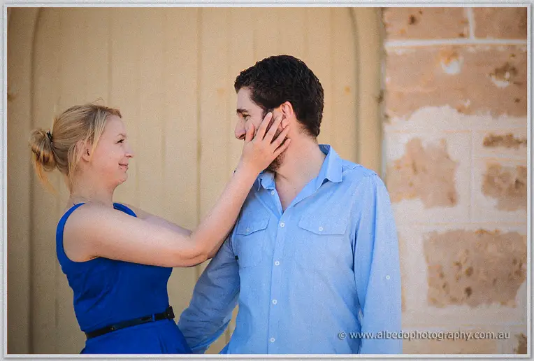 Julie cradles Dale's cheek in front of a weathered timber door in golden light
