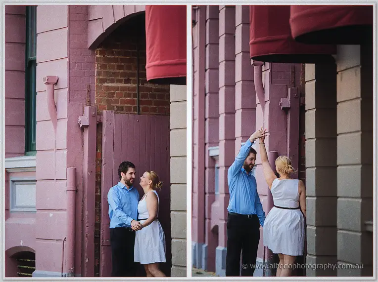 Dale twirls Julie by a dusty pink weatherboard wall, her white dress swinging