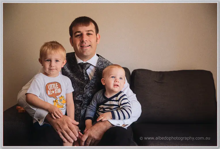 Max smiles on the couch with his two little boys snuggled close, quiet moment before dressing for the day.
