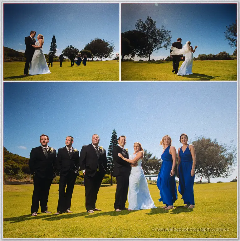 Olivia and Max embrace on a green lawn as veil flies and the barefoot bridal party lines up under blue sky.
