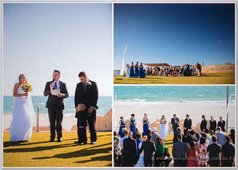A celebrant speaks into a microphone as Olivia, Max and their page boy stand by the turquoise sea.