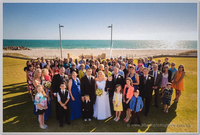 Olivia and Max sign the marriage register with their sons beside them, a seagull perched close by.