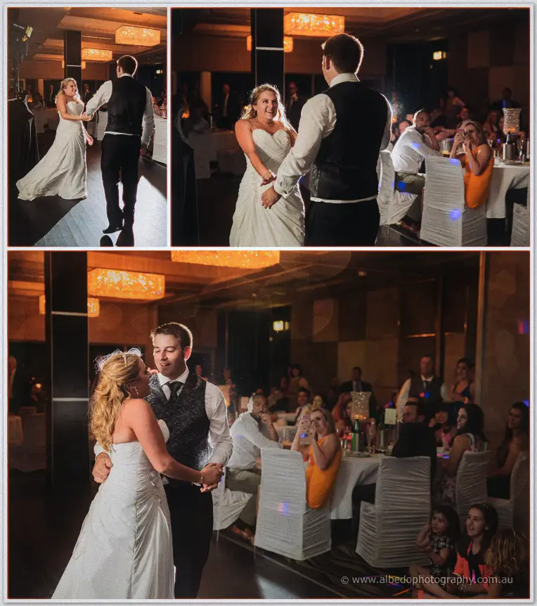 Olivia and Max share their first dance under chandeliers as guests watch from candlelit tables.