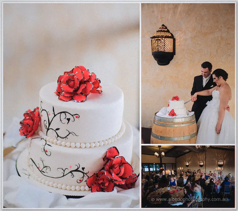 Sarah and Chris cut their white two-tier cake topped with red roses, set on a wine barrel at the reception.