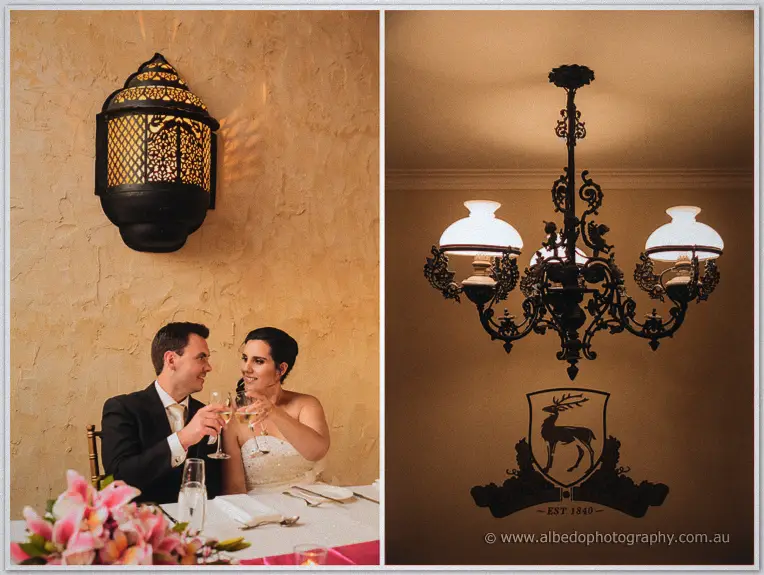 Sarah and Chris toast with champagne at their sweetheart table beside lantern light and a stag crest.