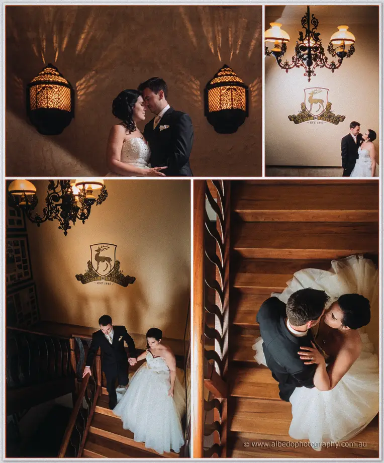 Sarah and Chris descend a timber staircase beneath a stag crest and chandelier, forehead to forehead.