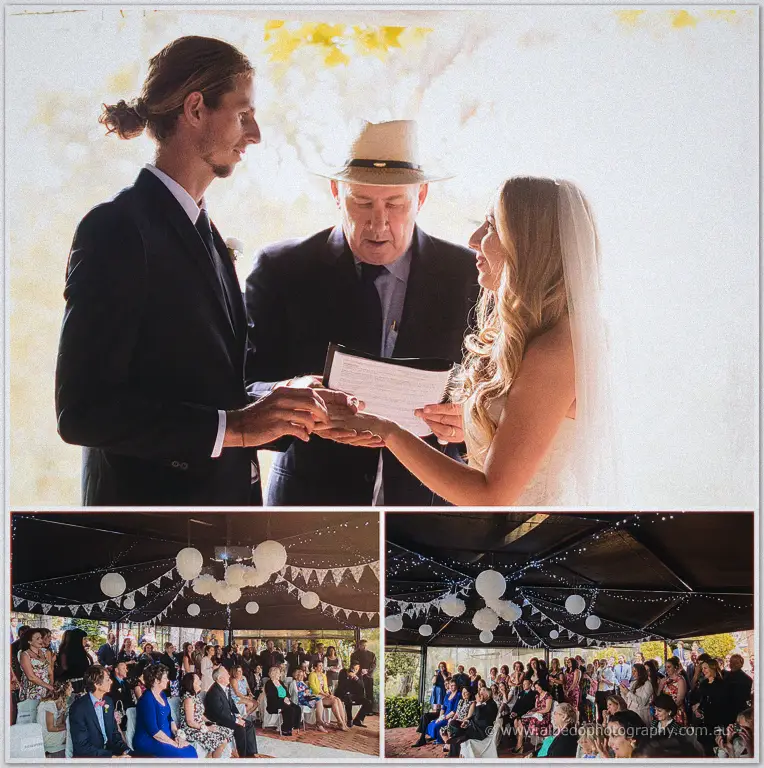 Tara and Stephen exchange vows before a straw-hatted celebrant as guests watch from the lantern-lit pavilion