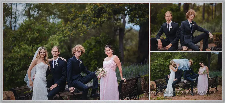 The bridal party lounges on a garden bench, the groomsmen in dark suits beside the bridesmaid in blush pink