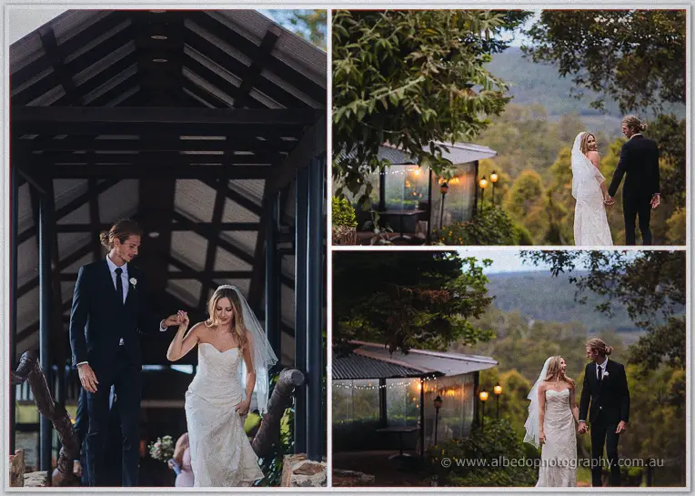 The newlyweds walk down from the timber pavilion toward lanterns glowing at dusk