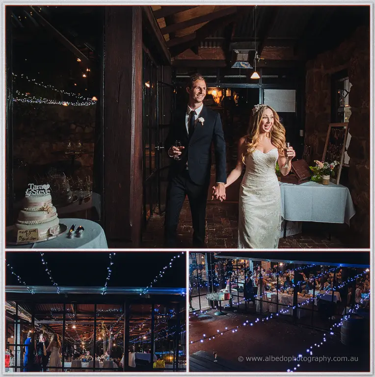 The newlyweds walk in with champagne past their pink cake as guests gather beneath night-time string lights