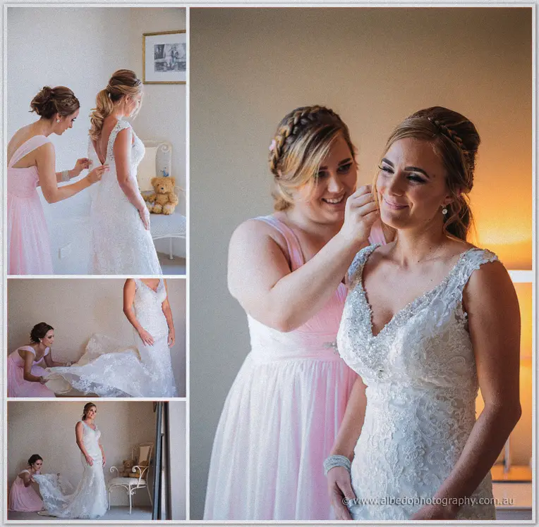 Bridesmaids in pink lace Tarmecca into her beaded gown, fastening buttons and arranging the lace train.