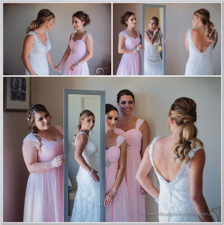 Tarmecca and her bridesmaids crowd a full-length mirror in pink gowns, laughing at her lace-gown reflection.