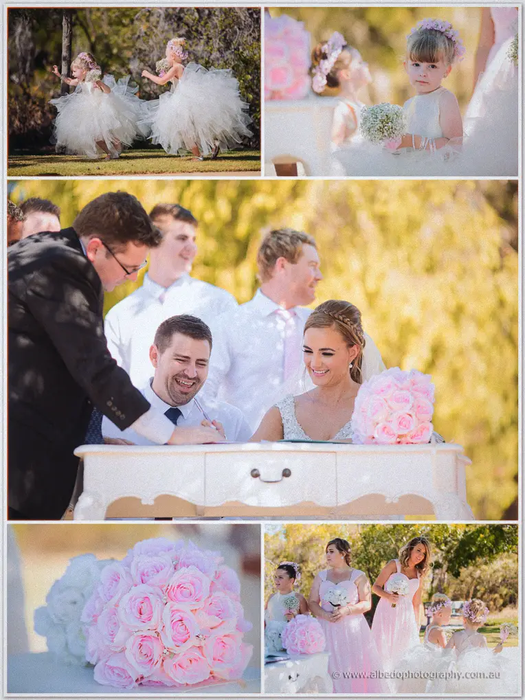 Flower girls twirl in tulle as the couple signs the register among pink roses and a pastel bridal party