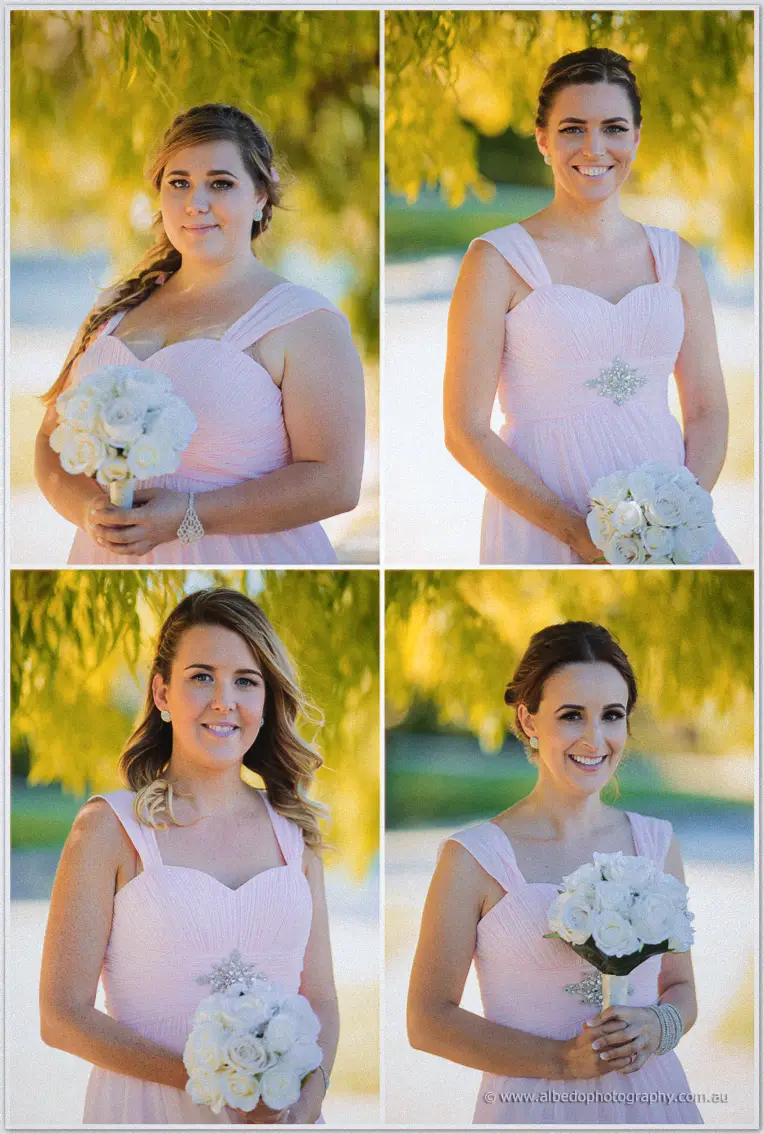 Four bridesmaids in blush pink dresses hold white rose bouquets under golden willow light
