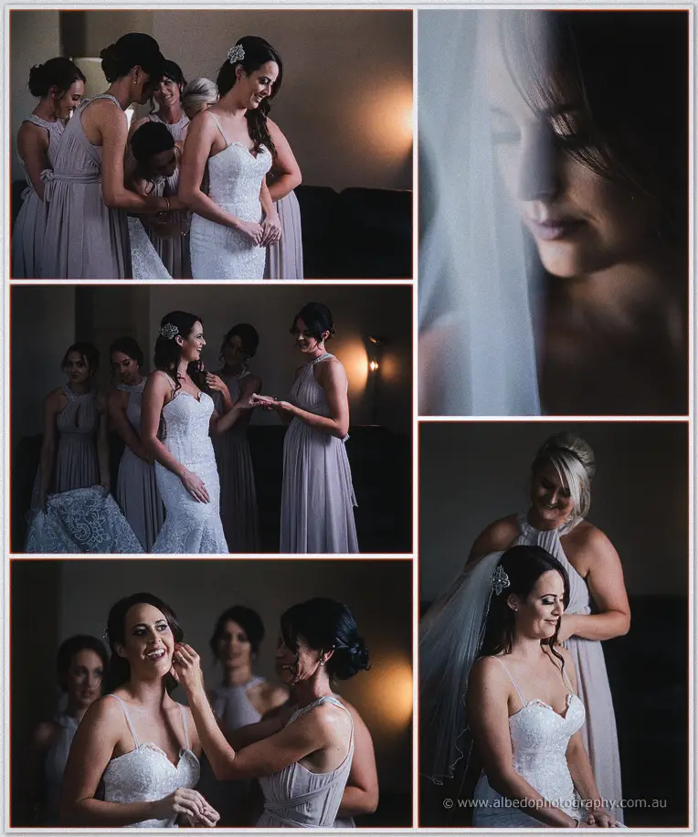 Bridesmaids in grey dresses helping Prue into her lace gown as her veil catches the light