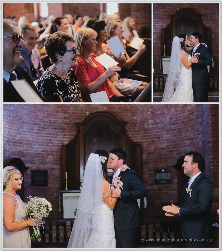 Guests smiling as Prue and Michael share their first kiss at the chapel altar