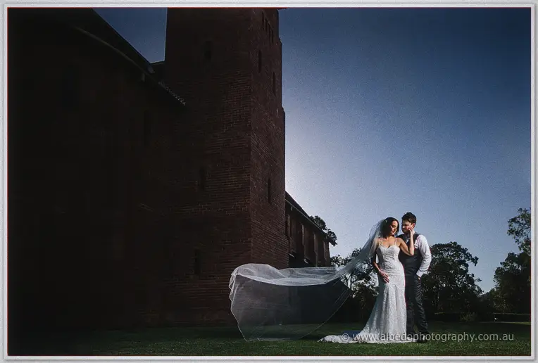 Prue and Michael beneath the chapel tower at dusk, her long veil streaming in the wind