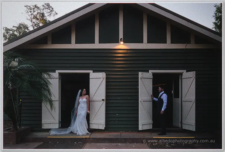 Prue and Michael posing in opposite doorways of the weatherboard hall at twilight