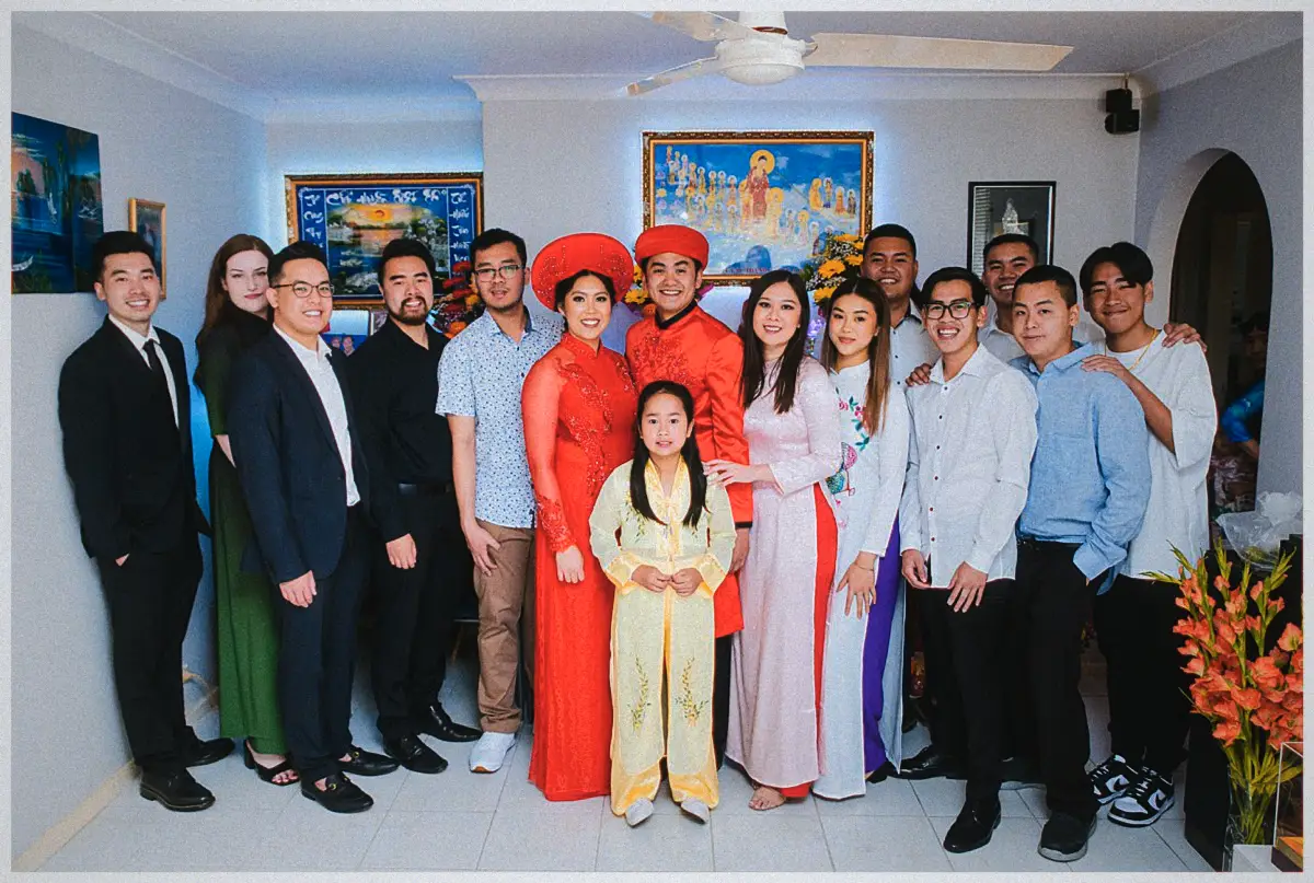 Natalie and Andrew in red ao dai pose with family and a young flower girl before the home altar