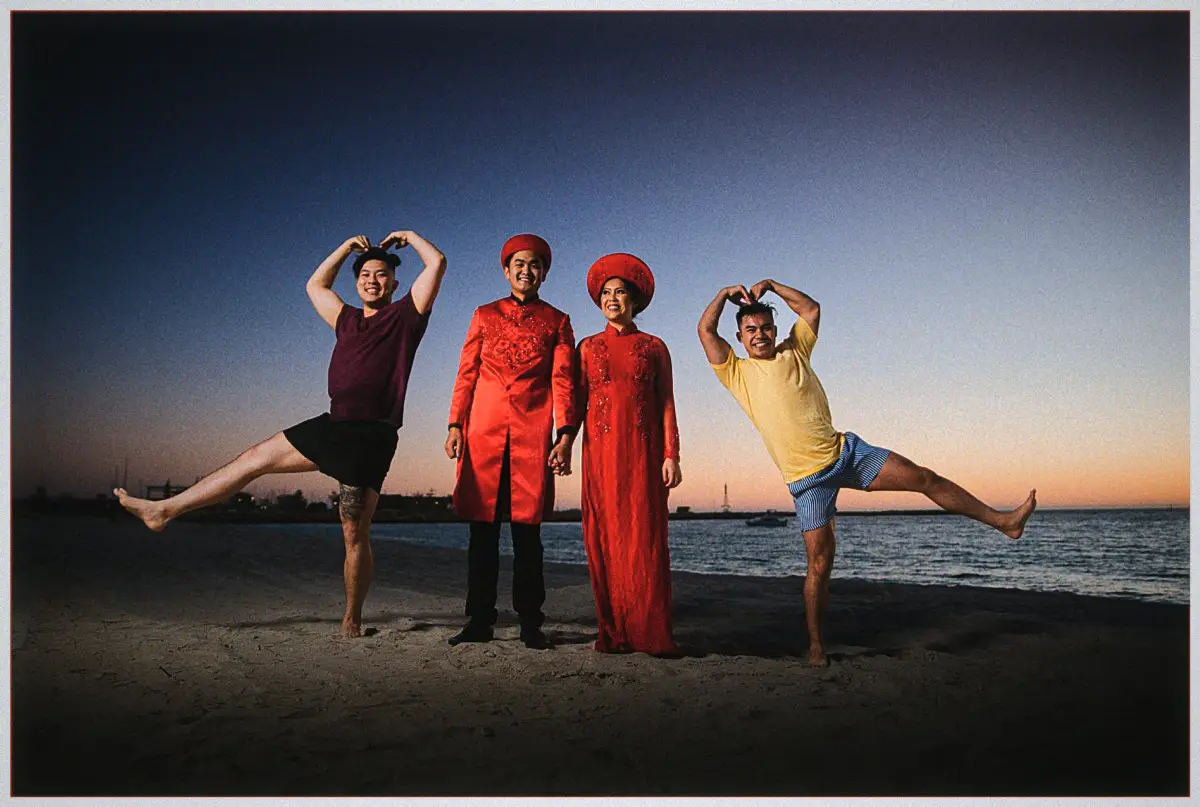 Natalie and Andrew pose on the beach at dusk while two friends strike playful heart poses