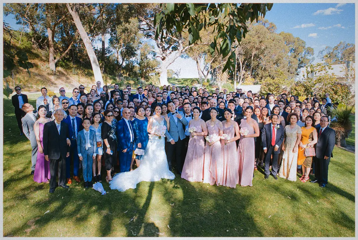 Natalie and Andrew gather their full guest list for a group photo on the tree-shaded Joondalup Resort lawn