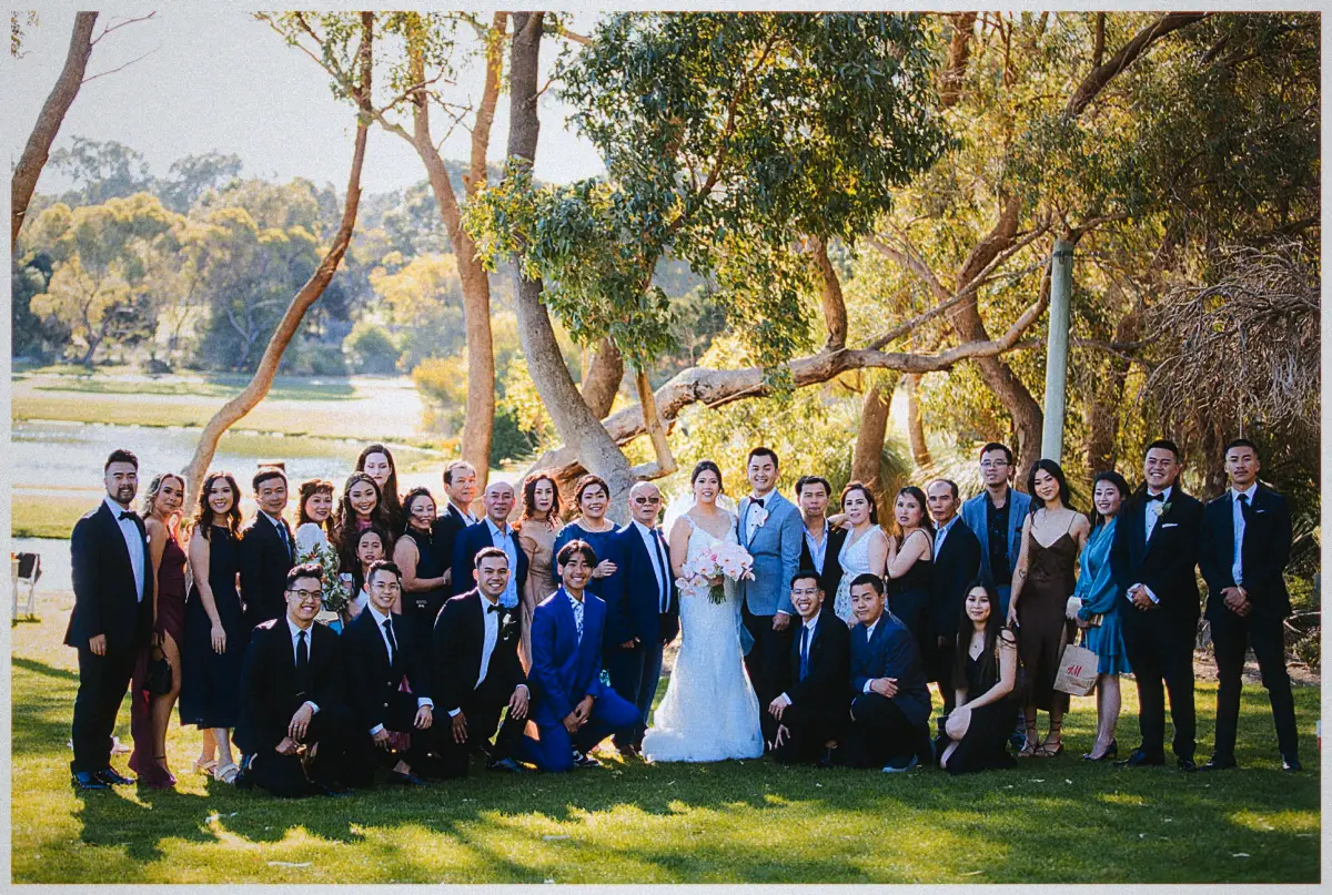 Natalie and Andrew gather extended family in suits and gowns for a lakeside photo under the gum trees