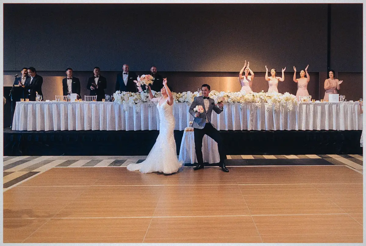 Natalie and Andrew strike playful dance poses with their bouquets before the floral-draped bridal table